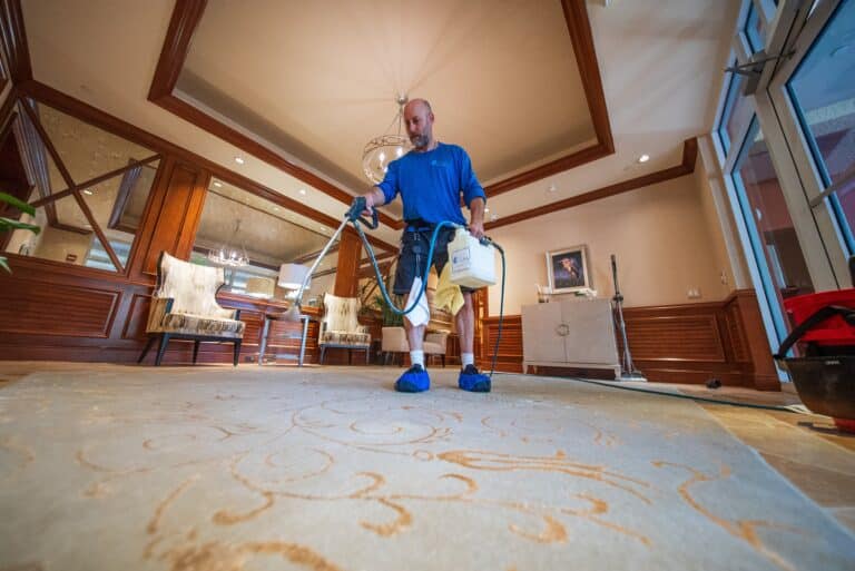 Technician applying pre-treatment to carpet before deep cleaning in Jupiter, FL.